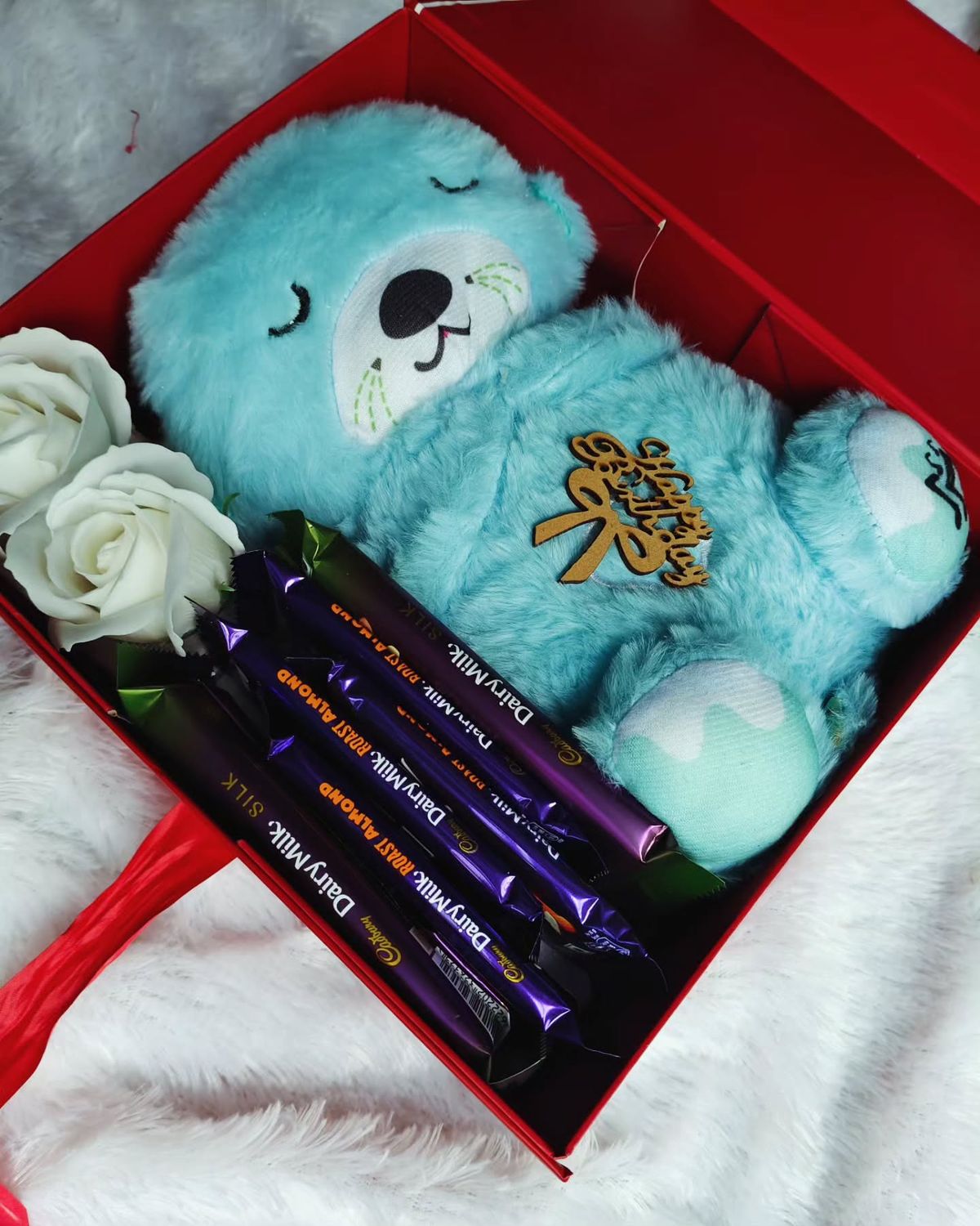 Red gift box with a cute blue plush bear and chocolates